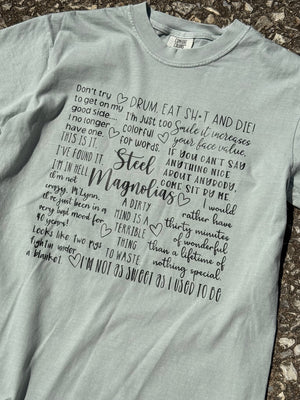 Front of light greenish-gray short sleeve t-shirt with "Don't try to get on my good side...I no longer have one. Drum, eat sh*t and die! I'm just to colorful for words. Smile it increases your face value. This is it. I've found it. I'm in H*ll. Steel magnolias. If you can't say anything nice about anybody come sit by me. and other quotes printed in black.  The shirt is laying on the floor.