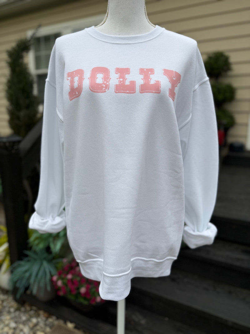 White sweatshirt with the word "Dolly" printed on the sweatshirt in pink. A mannequin standing in front of a front porch of a house is wearing the sweatshirt .