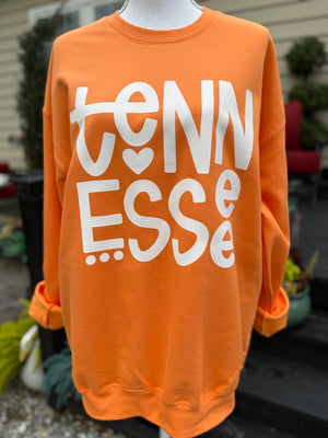 Orange sweatshirt with 'TENNESSEE' printed on it in white, displayed on a mannequin outdoors.