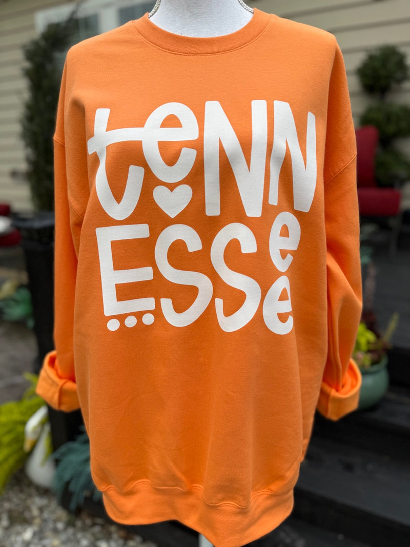 Orange sweatshirt with 'TENNESSEE' printed on it in white, displayed on a mannequin outdoors.