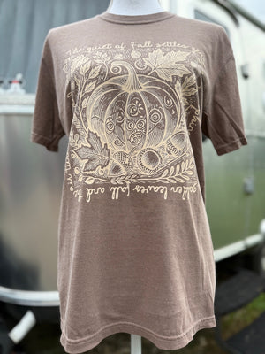 Brown t-shirt with a beige monochrome floral pumpkin design on a mannequin against a blurred background