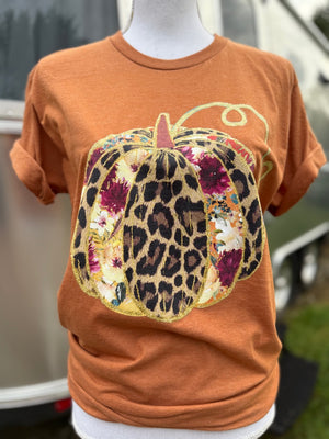 Orange t-shirt with a decorative pumpkin design featuring leopard print and floral patterns on a mannequin.
