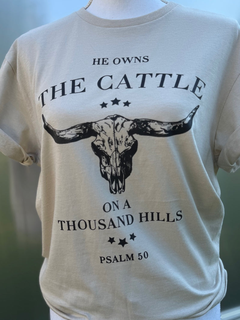 Cream T-shirt with longhorn skull with the text "He owns the cattle on a thousand hills. Psalm 50." printed on the shirt in black ink. 